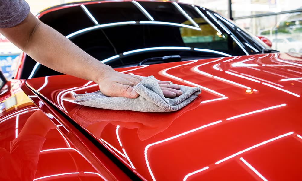 Auto detailer polishing a car hood by hand